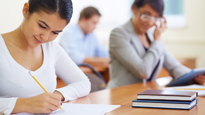 Women in a classroom, working on paper with pencil
