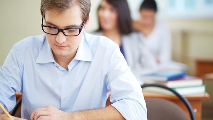 Man at desk writing with a pencil