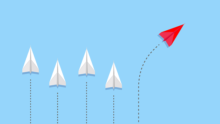 Paper airplanes in a line, with a red plane flying in a different direction