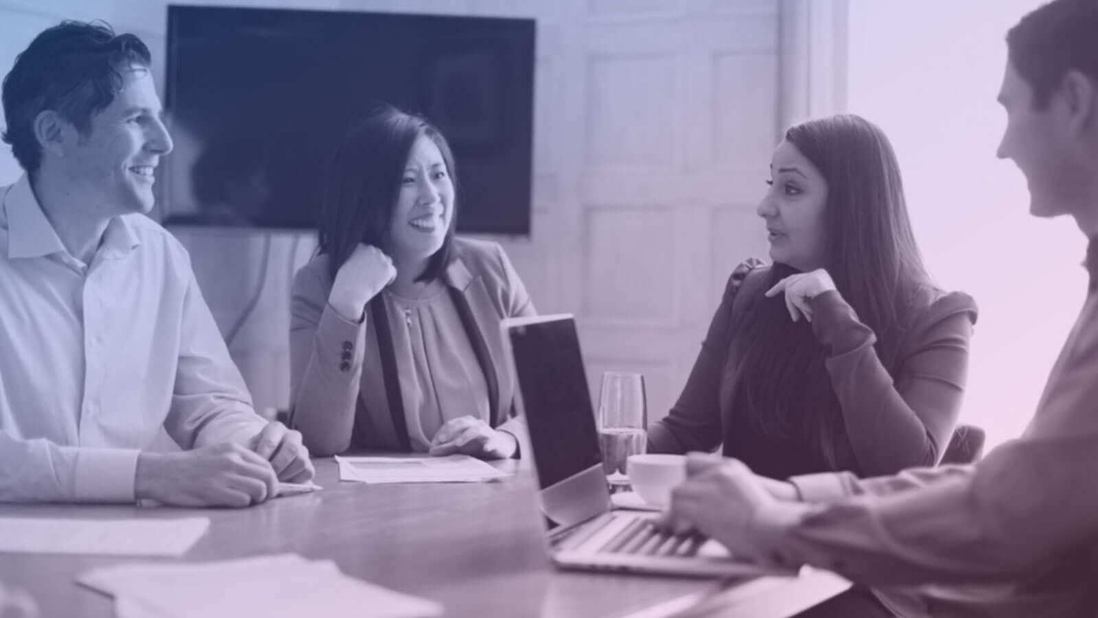 people sat around meeting table smiling