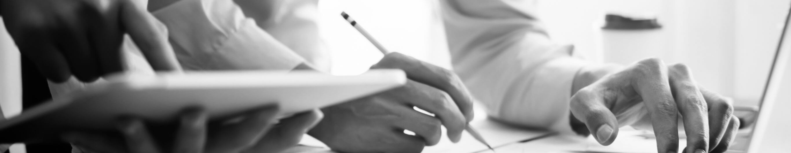 hands working at a desk and holding a tablet