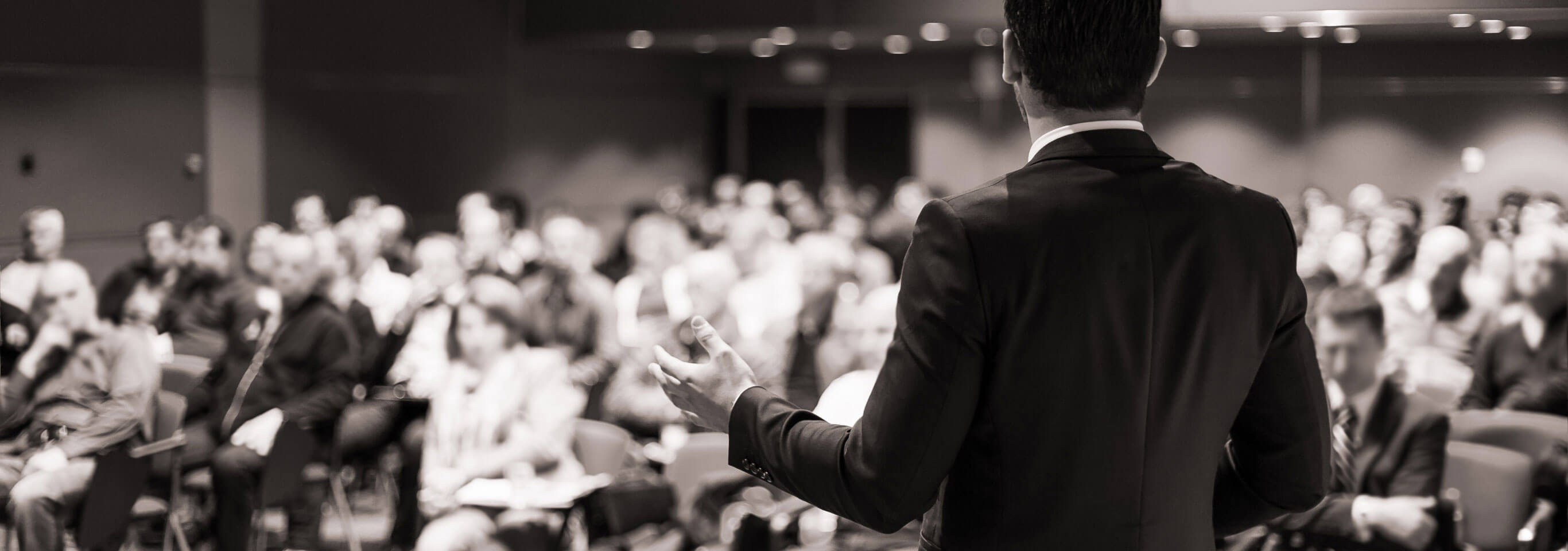 A man standing and talking to a group of people sitting down.